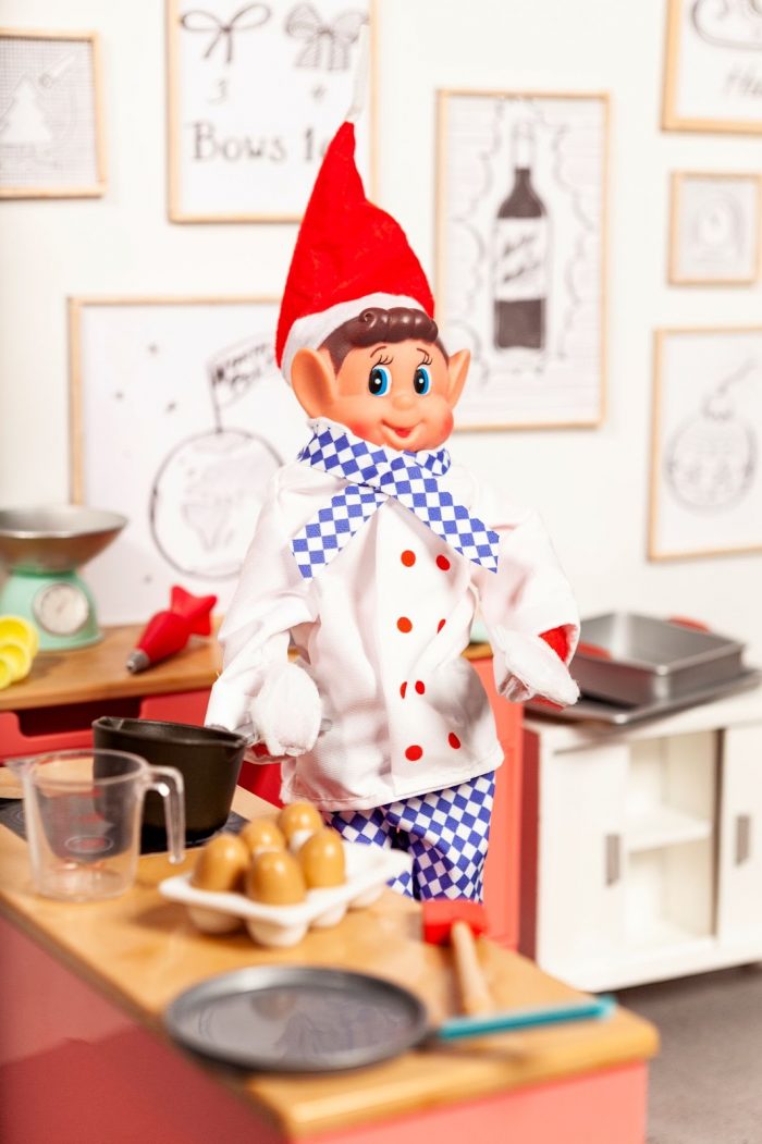 Elves Behavin Badly plush toy in a chef's outfit posed in a miniature kitchen